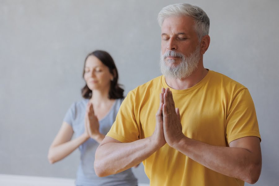 An adult European man and a young woman are engaged in breathing practice and physical exercises. Meditation for mental health.