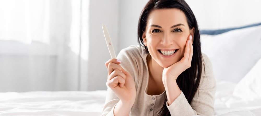Cheerful and beautiful woman holding a home pregnancy test