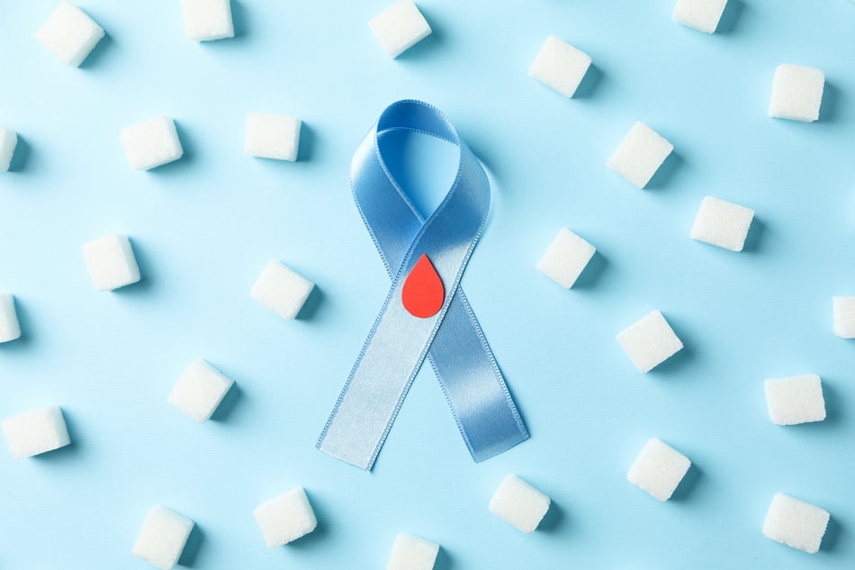 Diabetes awareness ribbon and sugar cubes on blue background. Diabetes risk factors concept.