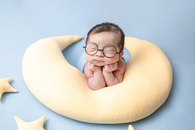 Newborn sleeping on crescent shaped pillow