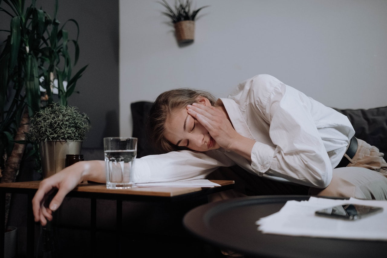 Exhausted Woman Falling Asleep on Table. Migraine attack leaving the woman tired.