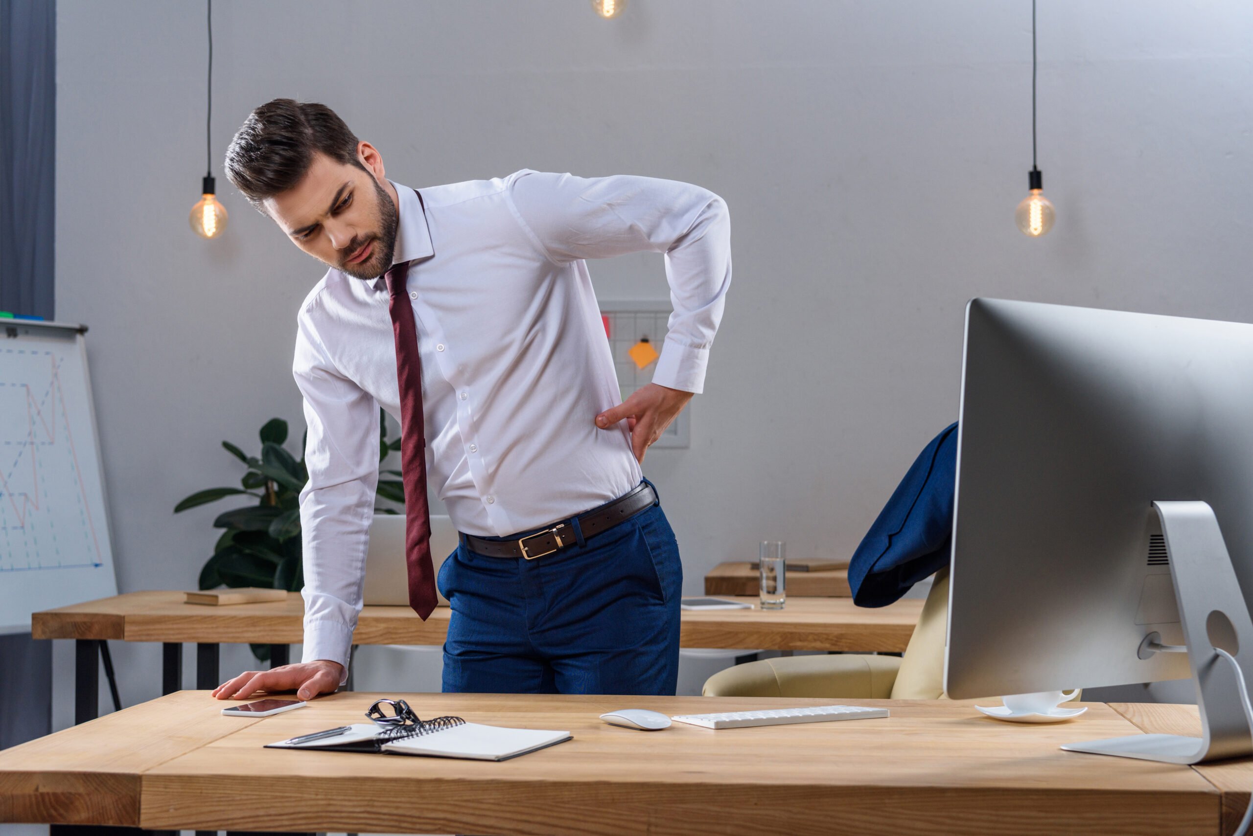 Young employee having back pain at work