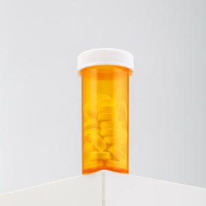 vertical-shot-yellow-container-filled-with-pills-white-table
