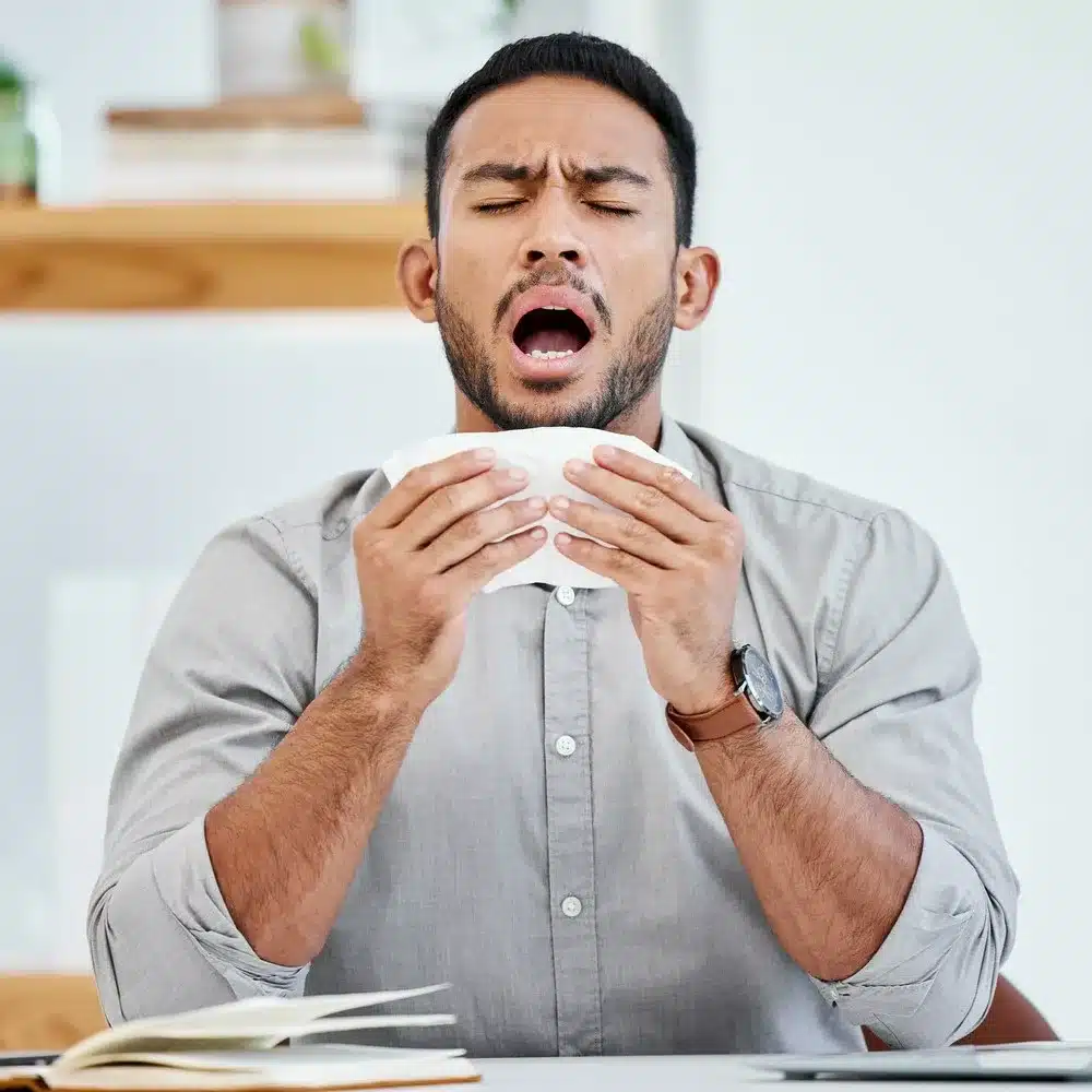 Oh no this is the worst time to get sick. Shot of a young businessman sneezing due to allergies. UAE weather and the common cold concept