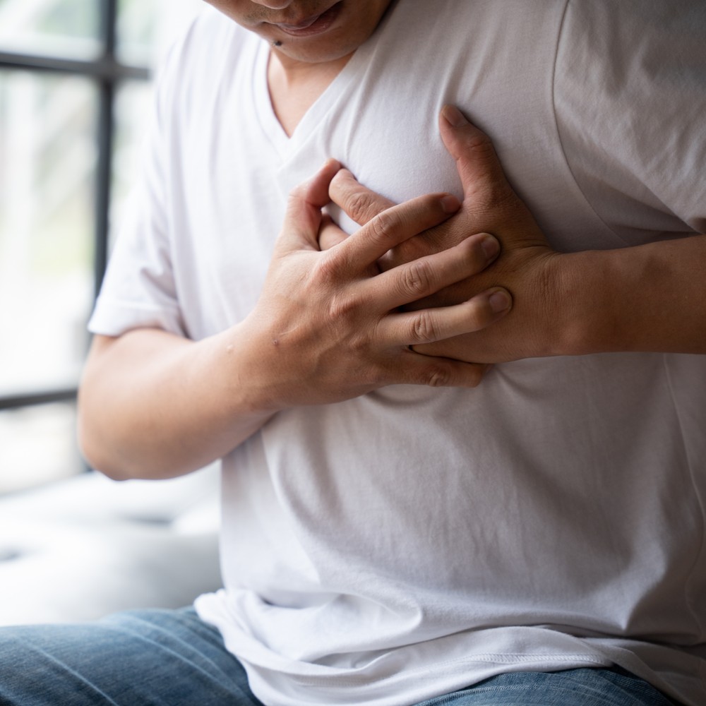 Hands holding chest with symptoms of heart attack disease, a man with a heart attack. What are the high cholesterol symptoms?